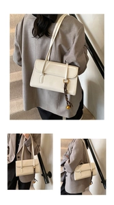 Detail view of cream minimalist underarm bag with decorative woven strap and metal charm