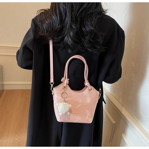 Sac seau rose brillant avec charme en fourrure sur manteau noir pour un style élégant