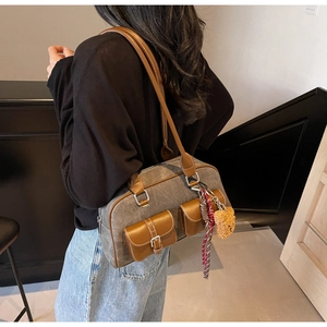 Detail of grey canvas and brown leather boston bag with charms on a female model