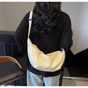 Chic beige pleated crescent bag with wide adjustable shoulder strap on female model