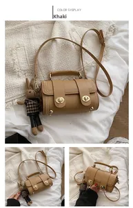 Detail view of khaki cylindrical PU leather bag with metal studs and cute bunny pendant
