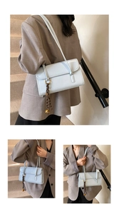 Detail of light blue patent leather underarm bag with braided cord and golden metal charms
