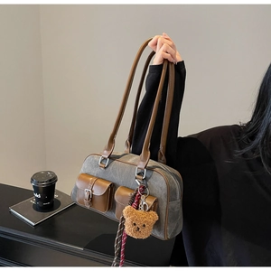 Detail of grey canvas and brown leather vintage tote bag with cute plush bear charm