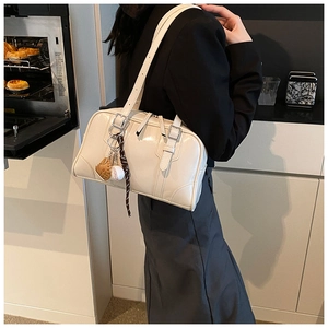 Detail of cream Boston bag with baseball charms and silk scarf on a long shoulder strap
