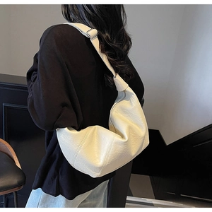 Detailed close-up of creamy white textured leather on a minimalist crescent crossbody bag