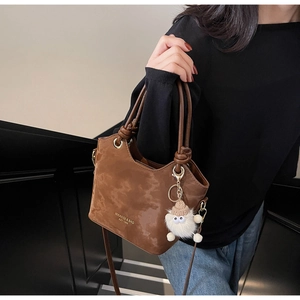 Détail d'un sac seau marron vintage avec poignée nouée et breloque pelucheuse