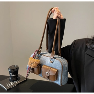 Detail of blue denim hobo bag with brown leather trim and cute teddy bear keychain