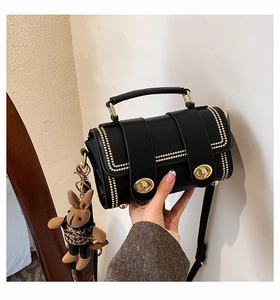 Detail of black leather crossbody bag with gold studs and a cute bunny plush charm