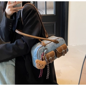 Detail view of retro color-block boston bag with leather pockets and plush bear charm