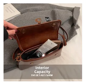 Macro detail showing interior storage capacity with phone and cosmetics in dark brown bag