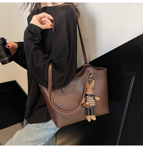 Détail d'un grand sac cabas marron foncé en cuir vintage avec un pendentif lapin mignon