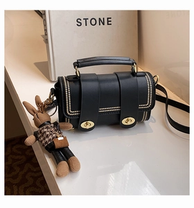 Detail of black crossbody bag with gold studs, twist locks, and houndstooth bunny charm