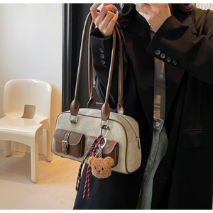 Detail view of contrast canvas shoulder bag with leather pockets and plush bear charm