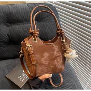 Détail du sac seau marron en daim avec poignée nouée et pendentif agneau en peluche