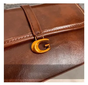 Detail of vintage brown leather handbag featuring a polished gold G-shaped metal buckle