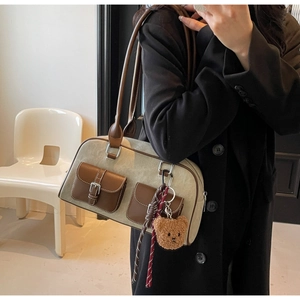 Detail of vintage canvas and leather shoulder bag with plush bear charm and pockets