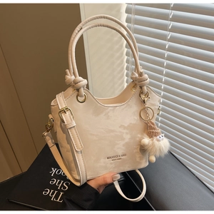 Vue détaillée du sac seau crème avec texture marbrée et pendentif en peluche doux
