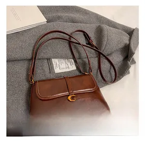 Detail of vintage brown leather handbag with gold buckle and adjustable shoulder strap