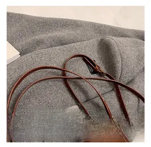 Detail of adjustable leather shoulder strap with brass buckle on a brown square bag