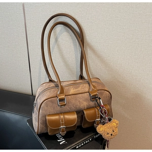 Close-up of vintage brown Boston bag featuring dual front pockets and a cute bear charm