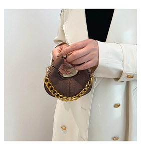 Detalle de bolso medialuna en ante marrón oscuro con cadena dorada y costuras finas