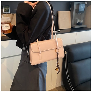 Detail of light pink oil wax leather underarm bag featuring a brown woven tassel pendant