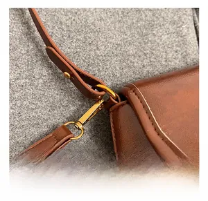 Detail of the high-quality brass metal hook and strap connection on the brown leather bag