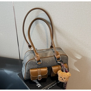 Retro canvas and brown leather shoulder bag with small bear pendant on a black seat