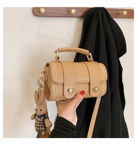 Detail of camel retro handbag with white stitching and a cute leopard print bunny charm