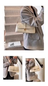 Detail of cream leather shoulder bag featuring a gold G-shaped buckle closure