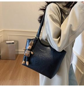 Détail d'un sac cabas en cuir noir avec un pendentif lapin et un texte de mode