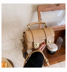 Detailed shot of a khaki retro crossbody bag with beaded trim and dual gold twist locks