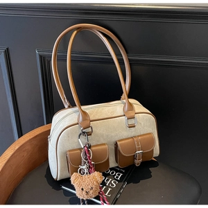 Detail view of retro Boston bag with contrast stitching, side pockets and bear pendant