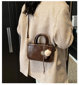 Détail d'un sac carré en cuir marron brillant avec pendentif glace en peluche