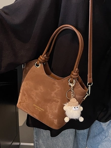 Sac seau marron mat avec lettrage doré et charmant petit monstre suspendu à la bandoulière