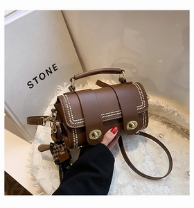 Detail of vintage brown cylinder handbag with white pearl straps and bear charm