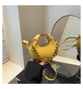 Detalle del mini bolso de media luna amarillo de ante con cadena dorada y correa delgada