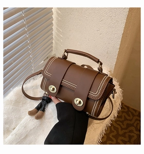 Close-up of retro brown contrast handbag with gold double twist lock and doll charm