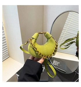 Detalle del bolso de ante verde aguacate con forma de medialuna y cadena dorada gruesa