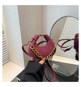 Detalle de bolso medialuna granate con cadena dorada y textura de ante suave