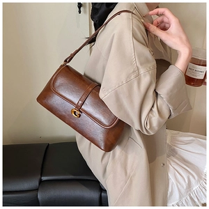 Close-up of vintage brown leather bag featuring a elegant gold C-shaped metal clasp