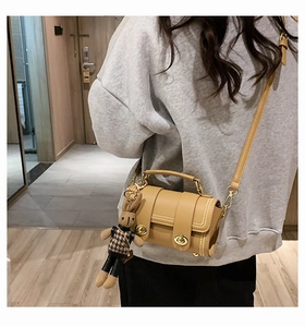 Detail of retro khaki crossbody bag with contrast stitching and a cute rabbit charm