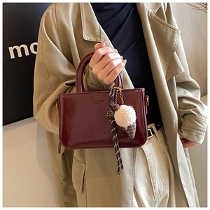 Dettaglio borsa in pelle cerata bordeaux con ciondolo a gelato in peluche e finitura lucida