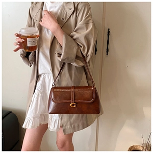 Detail of vintage brown leather handbag featuring a golden G-shaped metallic buckle