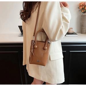 Detail of caramel oil-wax leather mini bag with spherical handle and logo lettering