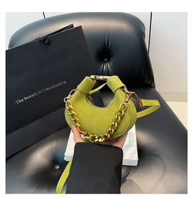 Detalle de bolso medialuna de gamuza verde con cadena dorada y costuras de precisión
