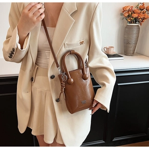 Detail view of brown glossy leather mini crossbody bag with unique spherical handle joints