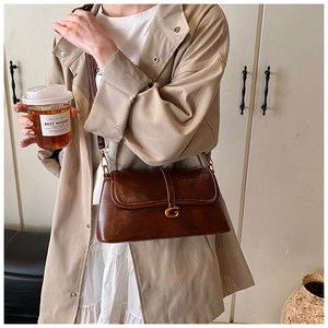 Detail of vintage brown leather handbag with gold G-buckle and elegant rectangular flap