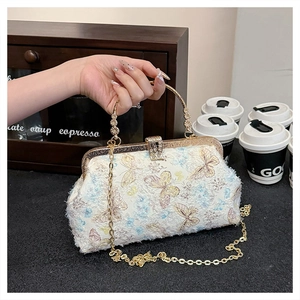 Detail der bestickten Schmetterlingsmuster und des goldenen Ringgriffs der Tasche
