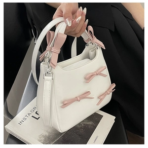 Close-up of white PU leather crossbody bag with pink bows and gold metal hardware detail
